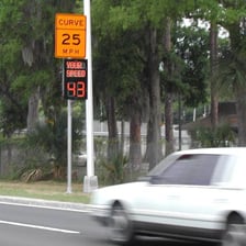 A car passing a roadside speed-limit sign