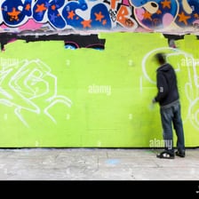 Graffiti artist painting a stylized tag on a wall