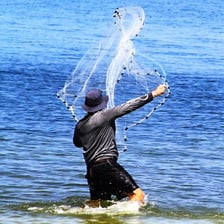 A fisherman casting a net across the water.