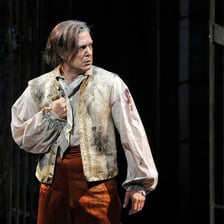 A male opera singer performing in a low vocal register.