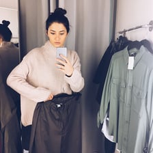 A person trying on clothing in a fitting room.