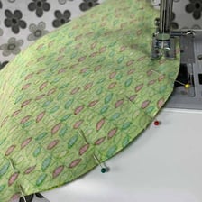 A straight sewing pin securing a piece of fabric.