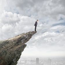 A person in a dangerous position near a mountain cliff