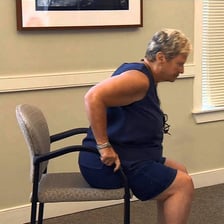A person rising from a chair.