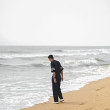 A person standing on a sandy beach beside the water