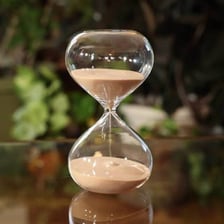 An hourglass with sand flowing between its chambers.
