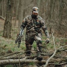 A hunter dressed in camouflage clothing in a wooded setting