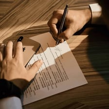 A person signing an official document to certify it.