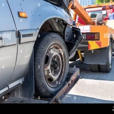 A tow truck pulling a disabled car from a highway