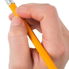 A hand using an eraser to remove pencil marks from paper