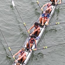 A rowing crew propelling a boat with oars.
