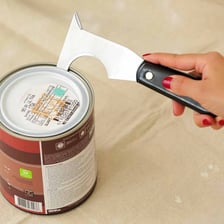 An open metal can of paint with a brush nearby