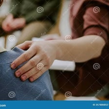 A person giving another person a gentle pat on the shoulder