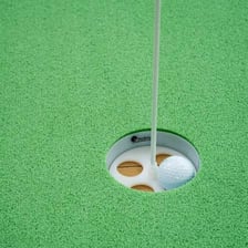A golf hole marked by a flag on a putting green.