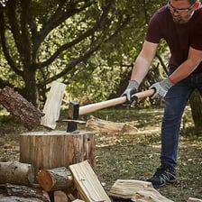 An axe being used to chop a piece of wood.