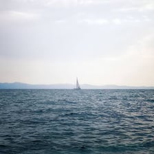 A sailboat traveling across open ocean waters