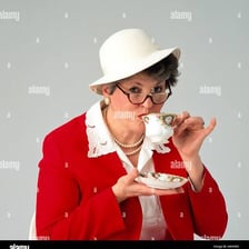 A person taking a small sip from an elegant teacup