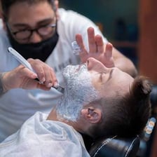 A barber giving a customer a traditional razor shave