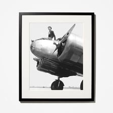 Amelia Earhart posing in front of an airplane