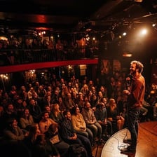 A stand-up comedian performing before a laughing audience.