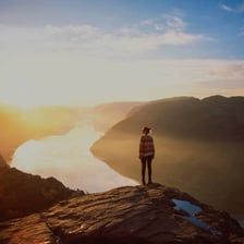 A person looking in wonder at a dramatic mountain landscape.