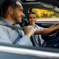 A teenager practicing driving a car