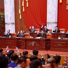Legislators voting in favor by raising their hands
