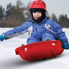 A child riding a sled down a snowy hill