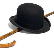 Charlie Chaplin portraying the Tramp with a bowler hat and cane.