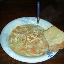 A piece of bread soaking up gravy from a plate