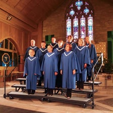 A choir performing while standing on tiered riser platforms.
