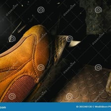 A driver’s foot pressing a car’s brake pedal