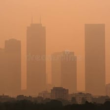 A city skyline partly hidden by a layer of gray smog.