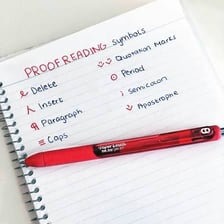 A proofreader marking corrections on a printed page.