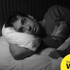 A person awake in bed at night while another person is nearby