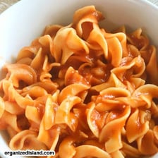 A bowl of pasta topped with tomato sauce.