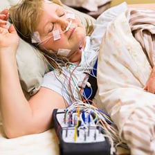 Patient undergoing an overnight sleep study with monitoring equipment.