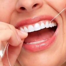 A person cleaning between their teeth with dental floss