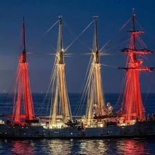 A sailing ship with several tall masts rising above its deck.