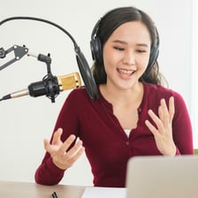 A radio personality speaking into a studio microphone during a broadcast.