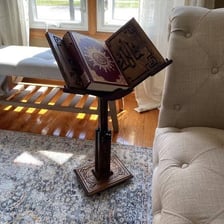 An open Quran resting on a traditional book stand.