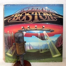 A radio microphone beside vinyl records associated with classic rock