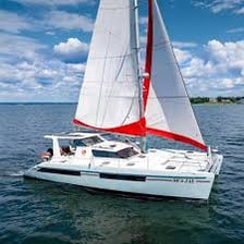 A catamaran sailing on the water with its sail raised.