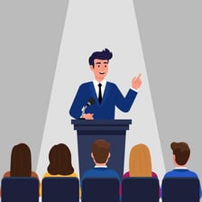 A speaker addressing an audience from a podium.