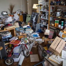 Piles of household possessions accumulated in a cluttered room.