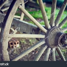 A wooden wagon wheel mounted on an axle.