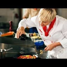 A sous chef preparing food in a commercial kitchen.