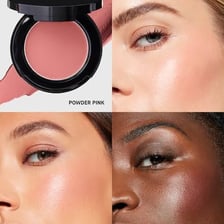 A makeup brush applying blush to a cheek