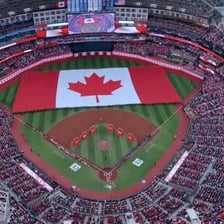 A crowd singing Canada's national anthem at a Toronto sports venue.