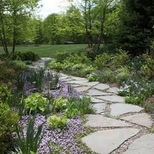 A worker laying paving stones to create a path.
